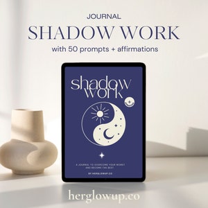 May include: A blue digital tablet with a white yin yang symbol and the text "shadow work" on the screen. The text "A journal to overcome your worst and become the best." is below the symbol. The text "By herglowup.co" is below the journal description. The text "herglowup.co" is at the bottom of the image.