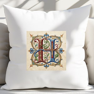 May include: White pillow with a decorative letter H in a colorful, ornate, medieval style. The letter is surrounded by a gold, red, blue, and green floral design.