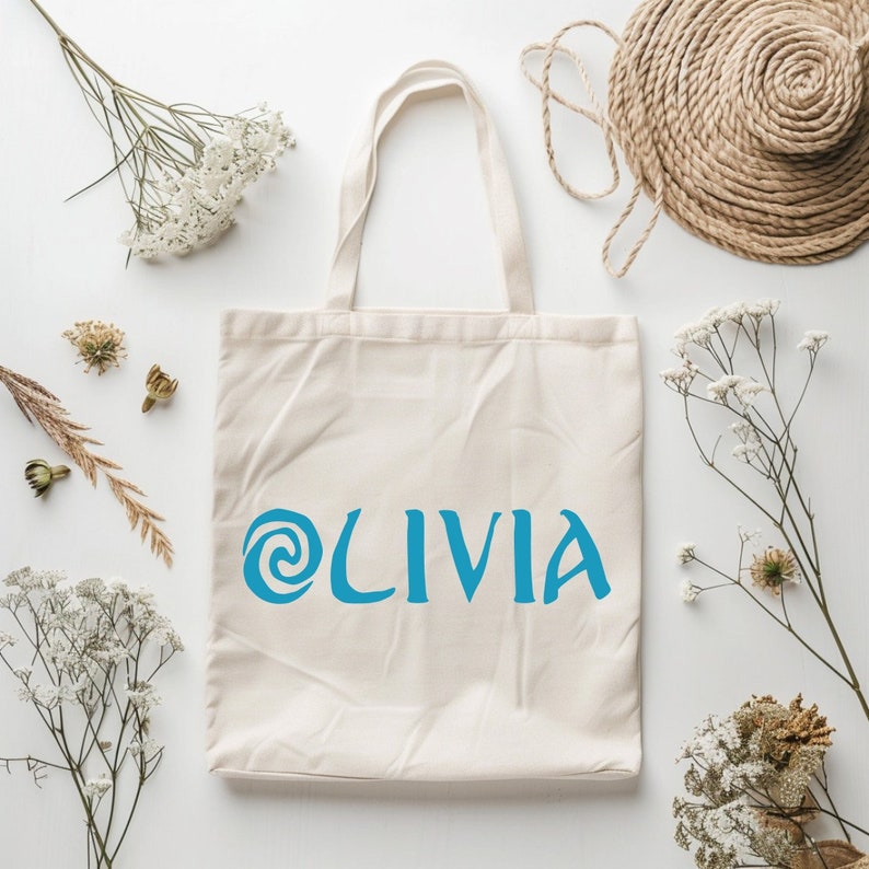 May include: A white canvas tote bag with a blue swirl design and the name 'OLIVIA' printed on it.