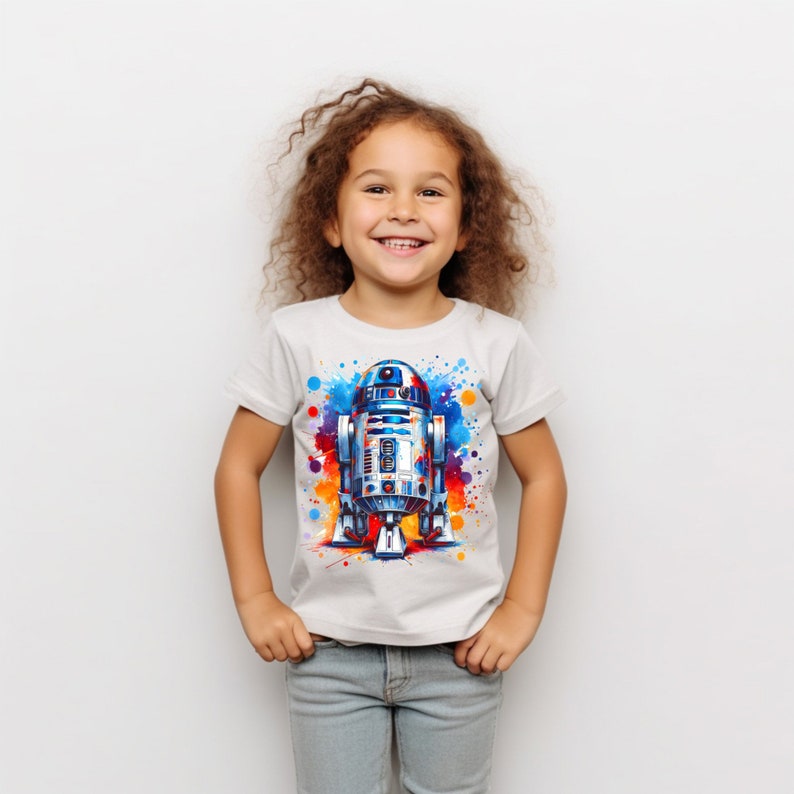 Puede incluir: Una persona joven con una camiseta blanca con un dise&ntilde;o de acuarela colorido de R2-D2, un robot popular de la franquicia Star Wars.