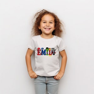 May include: White t-shirt with the name "EMILY" spelled out in colorful letters. Each letter features a different superhero character from the Avengers.