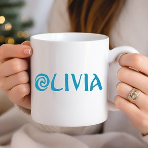 May include: A white ceramic mug with a blue swirl design and the name 'Olivia' printed on the front.