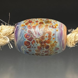 May include: Three colorful glass beads with a speckled pattern are strung on a natural fiber rope. The beads feature shades of blue, orange, and purple, creating a unique and artistic design. The beads are a decorative element.