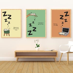 Puede incluir: Tres impresiones artísticas enmarcadas con un tema de gato de dibujos animados. Cada impresión presenta un gato durmiendo con símbolos "Zz" y texto. Los fondos son amarillos, verdes y naranjas. El texto incluye frases como "Despiértame" y "Confía en mí, estoy cómodo."