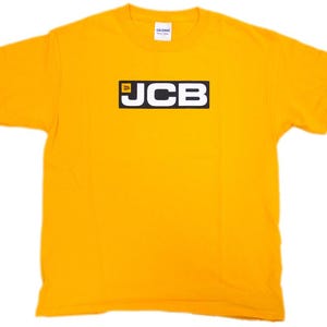 May include: A bright yellow short-sleeved t-shirt featuring a black rectangular logo on the chest with the white text JCB and a small yellow square icon. The shirt has a crew neckline and a white brand label visible at the inside of the collar.