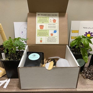 May include: A gardening kit containing plants, seeds, and tools. The kit includes a box with a planting guide, small plants in pots, seed packets, a small watering can, and a trowel. The kit is designed for planting.
