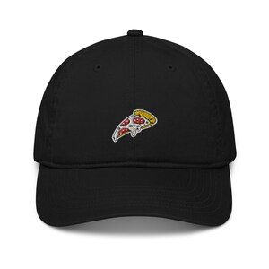 Puede incluir: Una gorra de béisbol negra con una imagen bordada de una rebanada de pizza. La pizza tiene pepperoni rojo, pimientos verdes y una corteza amarilla.