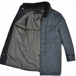 May include: A quilted, long coat in shades of gray and black, with a contrasting interior. The coat features a quilted pattern on the front and sleeves, a black collar, and a gray interior lining. The coat is open, revealing the interior lining and a zipper.