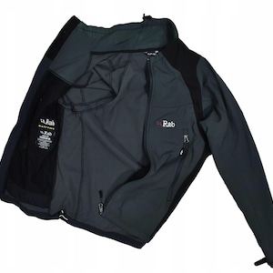 May include: A dark gray and black Rab softshell jacket with a full-length zipper. The jacket has a high collar, multiple pockets, and the Rab logo on the chest. The interior is a lighter gray color. The jacket is designed for outdoor activities.