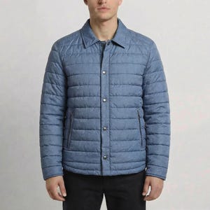 May include: A light blue quilted jacket with a button-up front and two side pockets. The jacket has a collared neckline and is worn with black pants. The jacket is a casual outerwear piece.