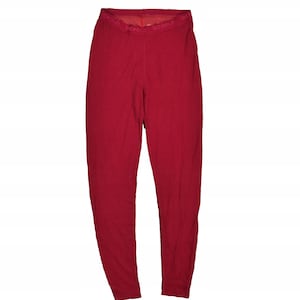Puede incluir: Un pantalón térmico de color rojo liso. La cintura lleva el nombre de la marca "Devold" en letras blancas. El pantalón está hecho de un material suave, posiblemente lana, y está diseñado para brindar calidez y comodidad.