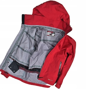 May include: A red hooded jacket with a gray interior. The jacket is open, revealing the inside lining and pockets. The jacket has a zipper closure and a small logo on the front. The jacket is designed for outdoor activities.