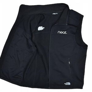 May include: Black vest with a zip-up front and a stand-up collar. The vest has the word "neat." printed on the chest and the North Face logo on the chest and back. The vest has two side pockets and a full interior lining.