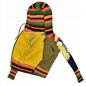 Puede incluir: Una colorida sudadera con capucha y cremallera con capucha y mangas a rayas. La sudadera con capucha presenta una mezcla de patrones, incluyendo rayas y diseños abstractos, con un interior amarillo y un pequeño bolsillo en una manga. La combinación de colores incluye tonos de amarillo, naranja y negro.