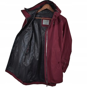 May include: A burgundy hooded jacket with a black interior lining, hanging on a wooden hanger. The jacket has a full-length zipper and a small tag with the letter "S". The jacket is made of a water-resistant material.