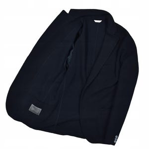 May include: A navy blue blazer with a classic design. The jacket features a notched lapel, a two-button closure, and a chest pocket. The interior lining is visible, and there is a small label on the inside. The blazer is made of a smooth fabric.