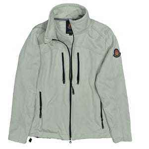 May include: A light gray softshell jacket with a high collar and a full-length black zipper. The jacket has three black zippered pockets and a small emblem on the upper left sleeve. The jacket is a neutral color and suitable for various activities.
