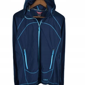 May include: A navy blue hooded jacket with a full-length zipper and two front pockets. The jacket features light blue stitching and a small "Rab" logo on the lower right. The jacket is hanging on a wooden hanger.