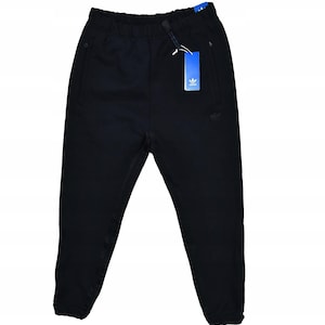Puede incluir: Pantalones deportivos negros con cintura con cordón y bolsillos laterales. Los pantalones presentan el logotipo de Adidas en la pierna y una etiqueta azul. Los pantalones están hechos de un material suave.