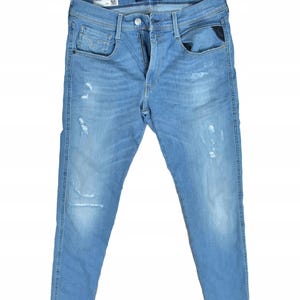 Peut inclure: Jean en denim bleu clair avec détails usés. Il présente une conception classique à cinq poches, une braguette zippée et le nom de la marque "REPLAY". Le jean a un délavage décoloré et une coupe slim.