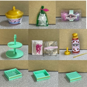 Könnte beinhalten: Ein Set mit Miniaturen in Puppenhausgröße zum Thema Süßwarenladen. Das Set enthält einen zweistöckigen Kuchenständer, eine Schachtel Süßigkeiten, eine Tüte Süßigkeiten, eine Flasche Sirup, eine Form für Süßigkeiten und eine Schachtel Süßigkeiten.