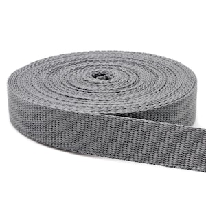 May include: A roll of gray webbing, a type of strong, woven fabric often used for straps, belts, and other applications.