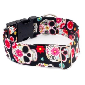 May include: A black dog collar with a colorful sugar skull pattern. The collar has a black plastic buckle and a silver metal D-ring.