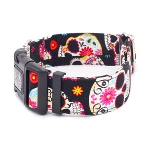 May include: Black dog collar with a colorful sugar skull pattern. The collar has a black buckle and a silver loop.