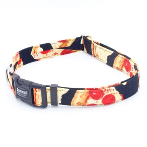 May include: A black dog collar with a pizza print. The collar has a black buckle with the text "Caminus Friends" on it.