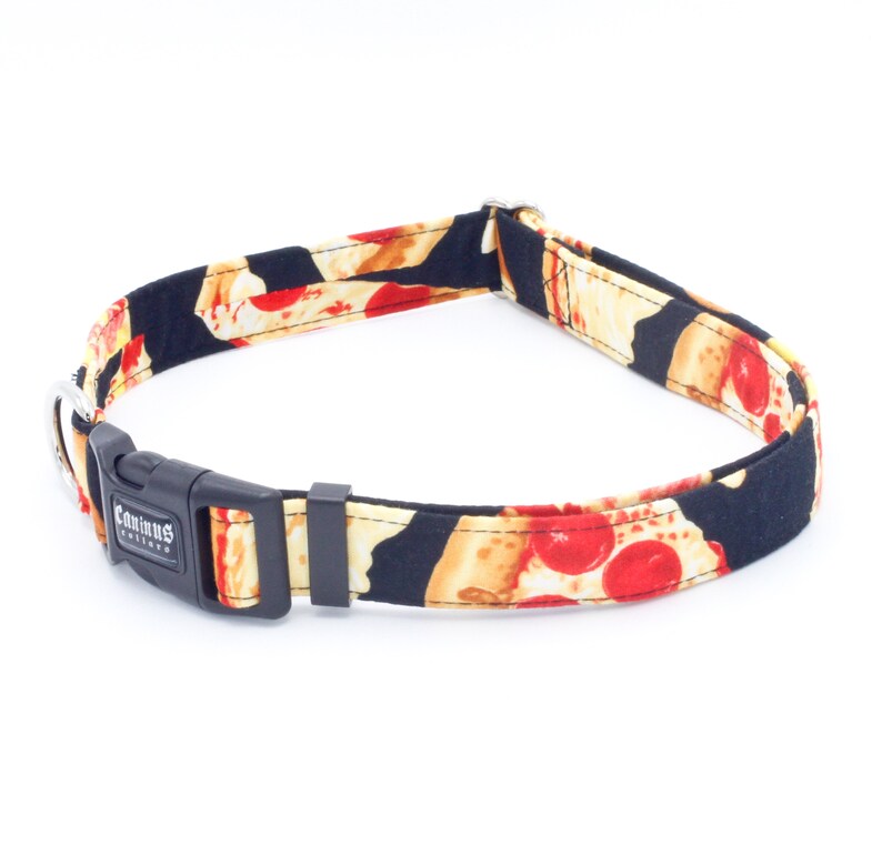 May include: A black dog collar with a pizza print. The collar has a black buckle with the text "Caminus Friends" on it.