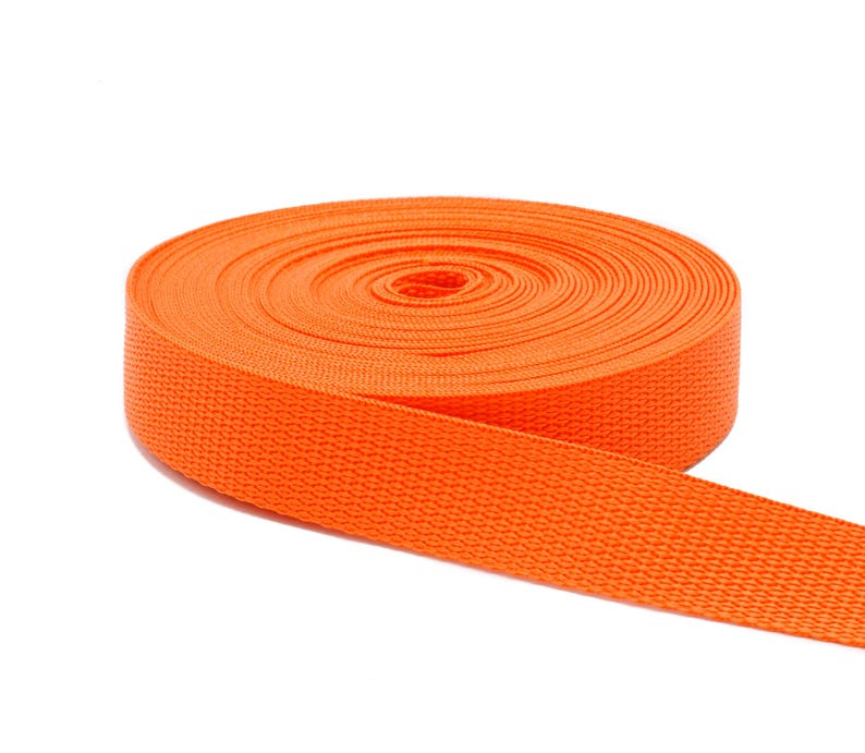 May include: A roll of bright orange webbing, a type of heavy-duty fabric used for straps, belts, and other applications.