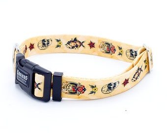 Op de afbeelding: Een beige hondenhalsband met een zwarte gesp en een kleurrijke tattoo-print met schedels, harten en bloemen. De halsband is gemaakt door Caninus Collars.