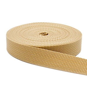May include: A roll of beige cotton webbing, a type of flat, strong fabric used for straps, belts, and other applications.