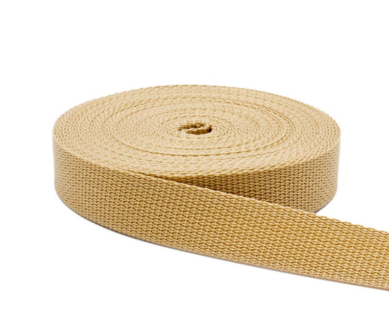 May include: A roll of beige cotton webbing, a type of flat, strong fabric used for straps, belts, and other applications.