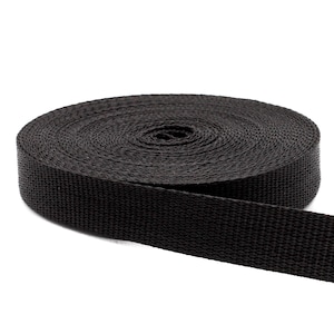 May include: A roll of black nylon webbing, a type of strong, durable fabric often used for straps, belts, and other applications.