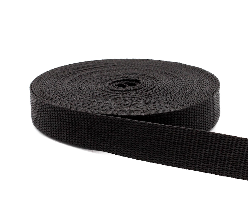 May include: A roll of black nylon webbing, a type of strong, durable fabric often used for straps, belts, and other applications.