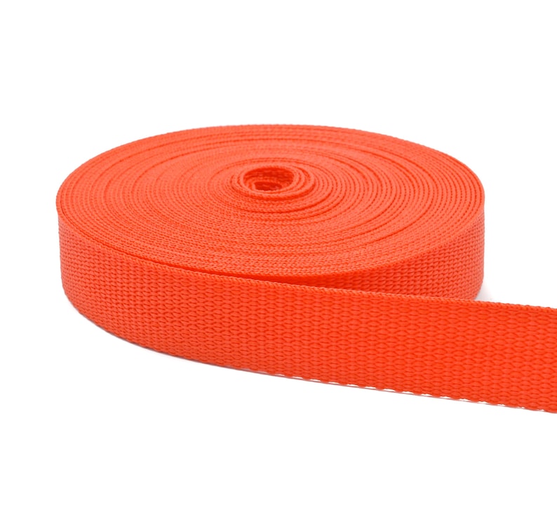 May include: A roll of bright orange webbing, a type of heavy-duty fabric used for straps, belts, and other applications.