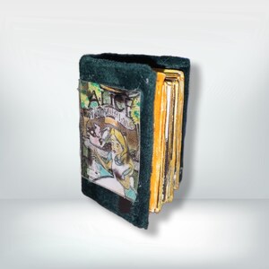 Peut inclure: Un petit livre vert foncé avec le titre "Alice au pays des merveilles" sur la couverture. Les pages sont jaunies. L'illustration montre Alice. Ce livre miniature est probablement destiné à l'exposition.