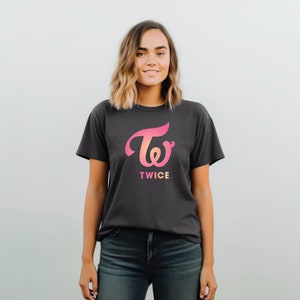 May include: A dark gray t-shirt with a pink and orange gradient graphic of the TWICE logo and the word "TWICE" in white text.