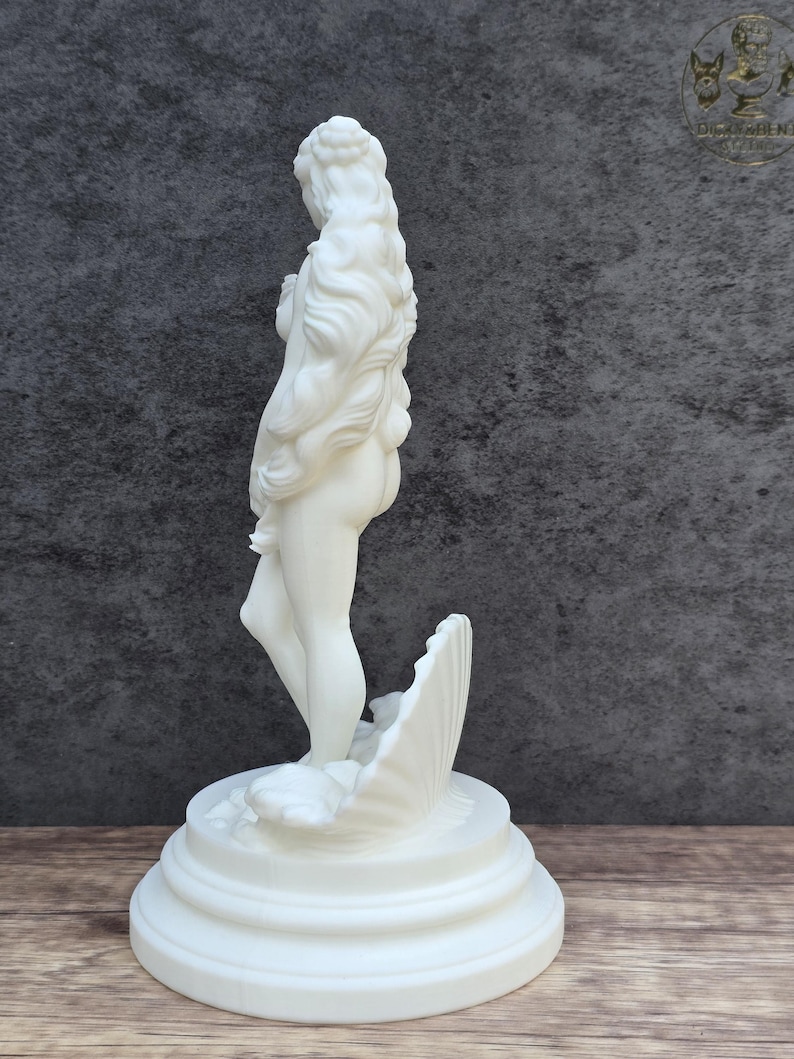 May include: A white matte sculpture of a standing figure with long flowing hair, positioned inside a large seashell. The figure is mounted on a circular tiered base, showcasing smooth surfaces and detailed contours throughout the entire form.
