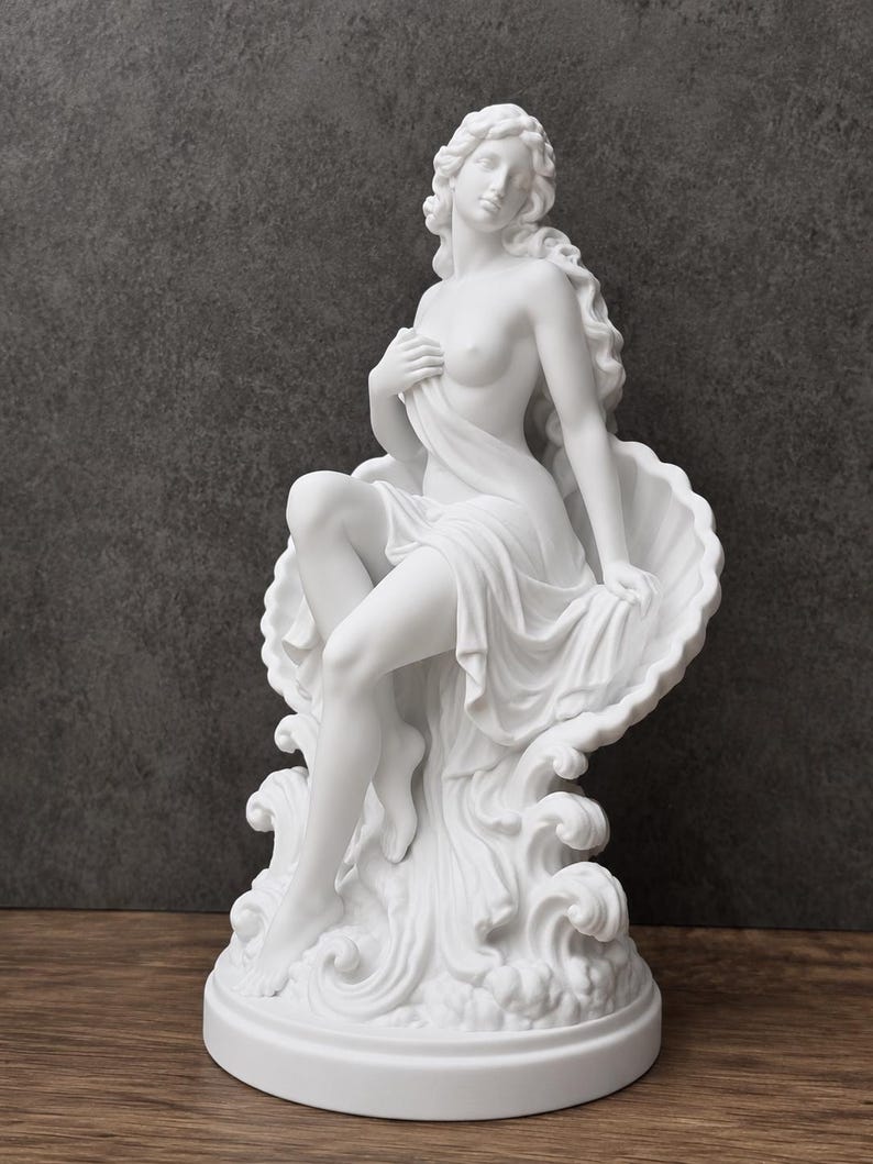 K&ouml;nnte beinhalten: Eine wei&szlig;e, matte Skulptur einer Figur mit langem, flie&szlig;endem Haar, die in einer gro&szlig;en, muschelf&ouml;rmigen Schale sitzt. Die Figur ist teilweise mit Stoff bedeckt, der &uuml;ber stilisierte Wellen f&auml;llt und auf einem runden Sockel ruht.