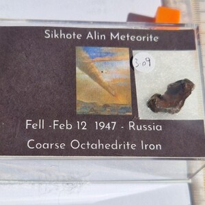 May include: A Sikhote Alin meteorite specimen in a clear display case. The label reads "Sikhote Alin Meteorite" and includes an illustration, date, and "Coarse Octahedrite Iron." A ruler shows measurements in millimeters.