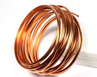 May include: A coil of copper wire, wound into a circle, on a white surface.