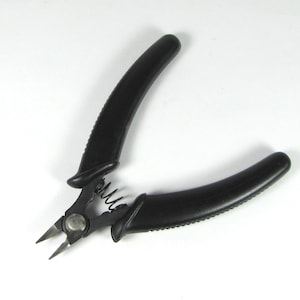 May include: Black wire cutters with black rubber handles. The cutters have a spring mechanism and a small metal rivet.