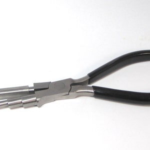 May include: A pair of silver-toned pliers with black rubber handles. The pliers have multiple interchangeable tips for different jewelry making tasks.