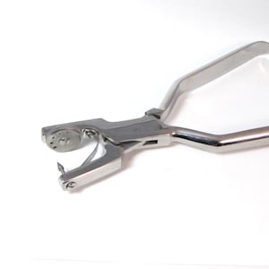 May include: A stainless steel dental banding pliers with a rotating dial and a sharp point.
