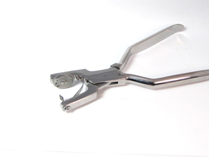 May include: A stainless steel dental banding pliers with a rotating dial and a sharp point.