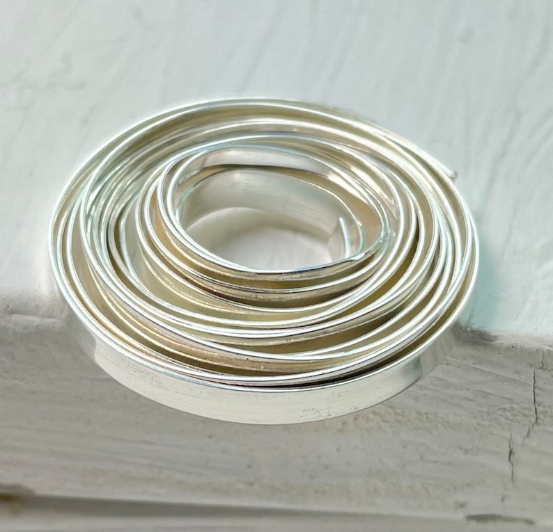 May include: A set of silver metal nested circle cutters, arranged in a spiral. The cutters are made of shiny, reflective metal and are designed for cutting dough or other materials into circular shapes. The cutters are of varying sizes.
