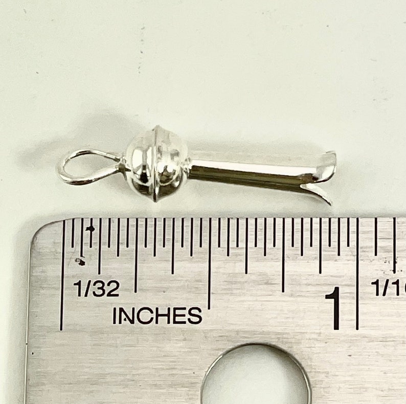 May include: Silver-toned metal clasp with a round ball on one end and a hook on the other. The clasp is about 1 inch long.