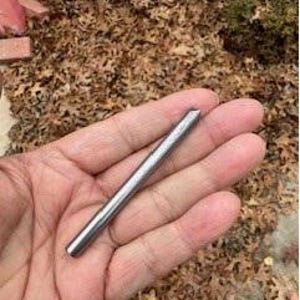 May include: A silver metal rod with a pointed tip. The rod is about 3 inches long.